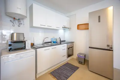 a small kitchen with white cabinets and a refrigerator at Angela's in Albufeira