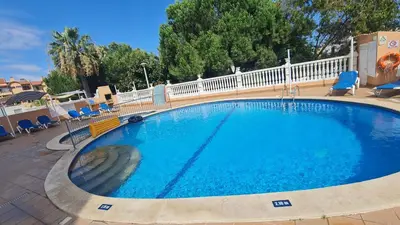 a large swimming pool with blue chairs and a fence at Sunbeam Home - Albufeira in Albufeira