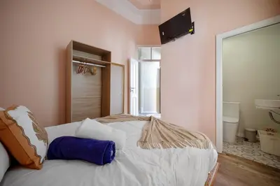 a bedroom with a white bed with a television on the wall at Vintage Senses Residences in Faro