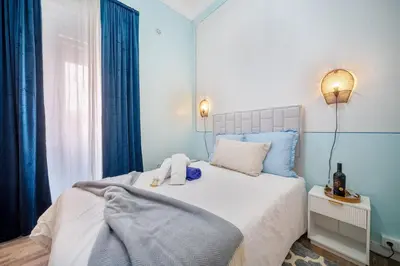 a bedroom with a large bed with blue curtains at Vintage Senses Residences in Faro
