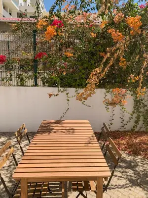 a wooden picnic table with two chairs and flowers at Moradia Mini Apartment in Faro