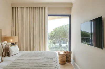 a bedroom with a large bed and a large window at Apartamento T2 renovado no Vila Sol com piscina in Vilamoura