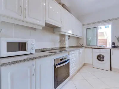a white kitchen with white cabinets and a sink at Apartamento JV com 2 quartos e piscina, Vilamoura in Quarteira