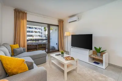 a living room with a couch and a flat screen tv at Vilamoura Retreat with Pool & Balcony by HostWise in Quarteira