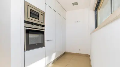a kitchen with white walls and a microwave at Cavalo Preto Ocean Breeze Apartment in Forte Novo Quarteira in Quarteira