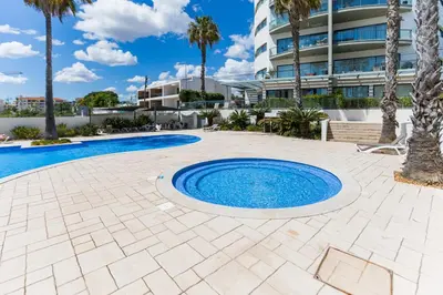 a pool with palm trees and a building at Cavalo Preto Ocean Breeze Apartment in Forte Novo Quarteira in Quarteira