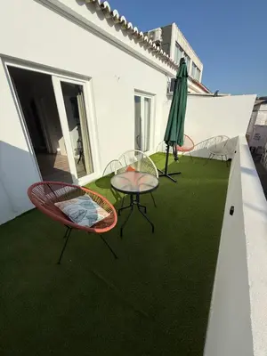 a patio with three chairs and a table and an umbrella at Camilas Place 2 in Bicas