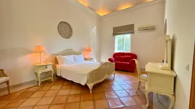 a bedroom with a bed and a red chair at Belinha - PINHEIROS ALTOS in Ludo