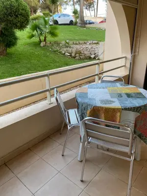 a table and chairs on a balcony with a view of a yard at Salgados Village, Santos Apartment in Guia