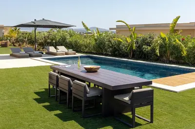 a wooden table and chairs next to a swimming pool at Faro Luxury Home with Heated Pool and Garden in Faro