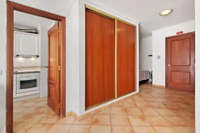 a room with wooden doors and a kitchen at Apartamento 16 - Quarteira in Quarteira