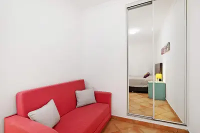 a red couch in a room with a mirror at Apartamento 16 - Quarteira in Quarteira