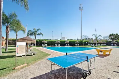 a ping pong table in front of a swimming pool at Apartamento 16 - Quarteira in Quarteira