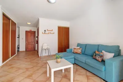 a living room with a blue couch and a table at Apartamento 16 - Quarteira in Quarteira