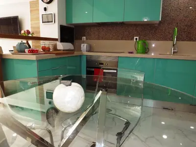 a kitchen with green cabinets and a glass table at Fantastic Apartment On The Beach in Albufeira