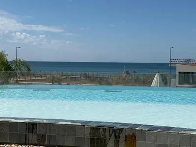 a large swimming pool with the ocean in the background at Quarteira Horizon Sea in Quarteira