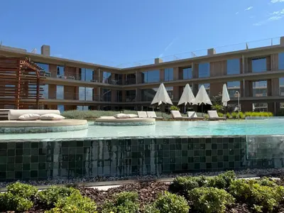 a hotel with a swimming pool with chairs and umbrellas at Quarteira Horizon Sea in Quarteira