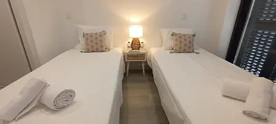 two beds in a room with a lamp on a table at Skynest 59 Faro Airport Guest House in Faro