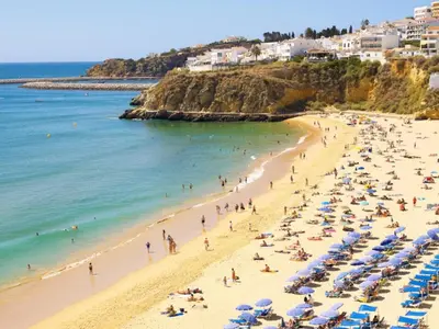 a beach with people and umbrellas and the ocean at Budget Beach Center - B4 in Albufeira