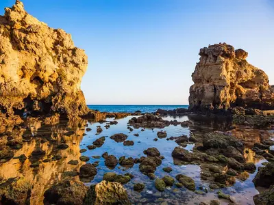 a view of a beach with rocks in the water at Ocean Breeze Rooms, Albufeira in Albufeira