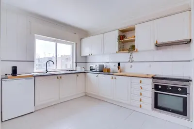 a white kitchen with white cabinets and a sink at Brisa Algarvia 1 in Faro