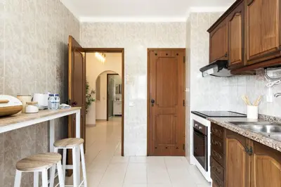 a kitchen with wooden cabinets and a counter top at Mare Viva - Seafront with pool by HD in Quarteira