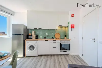 a kitchen with white cabinets and a washer and dryer at Peneco Beach Apartment Old Town in Albufeira