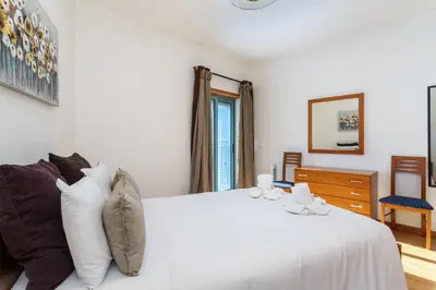 a white bedroom with a white bed and a window at Marina Paradis Bleu in Albufeira