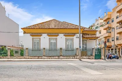 a white house with a fence in front of a street at Plaza Inn Hostel & Rooms in Faro