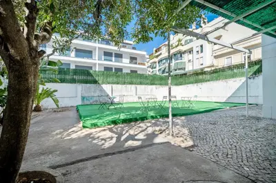 a tennis court with a green net next to a building at Plaza Inn Hostel & Rooms in Faro