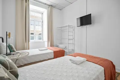 a room with two beds and a television on a wall at Plaza Inn Hostel & Rooms in Faro