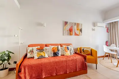 a bedroom with an orange bed with pillows at 1- bedroom flat in Vilamoura near the beach in Vilamoura