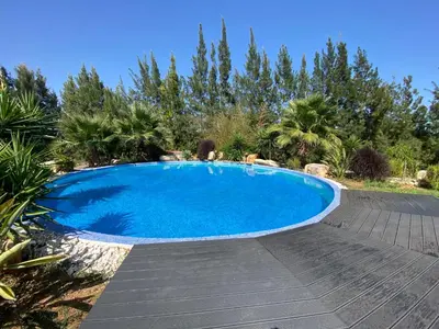 a large blue swimming pool with a wooden deck at Quinta Oriana Bella suite in Paderne