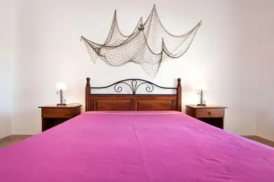 a bed with a pink bedspread and two night stands at Os Apartamentos A Ramos na Praia da Galé Estão inserido em Condomínio com PISCINA, Fica apenas a 350 Metros da Praia da Galé - Apartamentos com Ar Condicionado tanto nos Quartos como na Sala, Smart TV com Prime Vídeo e Cozinha Completa in Albufeira