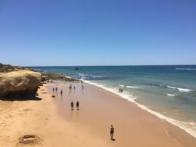 a group of people walking on the beach at Os Apartamentos A Ramos na Praia da Galé Estão inserido em Condomínio com PISCINA, Fica apenas a 350 Metros da Praia da Galé - Apartamentos com Ar Condicionado tanto nos Quartos como na Sala, Smart TV com Prime Vídeo e Cozinha Completa in Albufeira