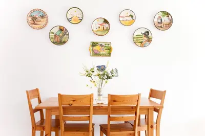 a dining room table and chairs with plates on the wall at Os Apartamentos A Ramos na Praia da Galé Estão inserido em Condomínio com PISCINA, Fica apenas a 350 Metros da Praia da Galé - Apartamentos com Ar Condicionado tanto nos Quartos como na Sala, Smart TV com Prime Vídeo e Cozinha Completa in Albufeira