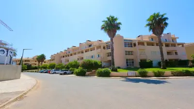 a large apartment building with palm trees and a street at Vilamoura Sul CD 312 - Cleverdetails in Quarteira