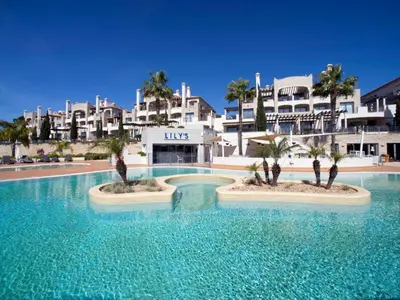 a large pool with palm trees in front of a building at Pine Hills Vilamoura in Quarteira