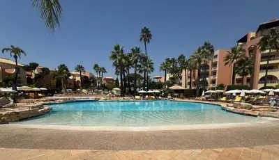 a swimming pool in a resort with palm trees and umbrellas at FourSeasons Vilamoura in Quarteira