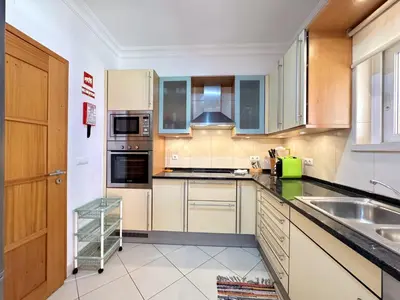a kitchen with wooden cabinets and a sink at Vilamoura Victoria Boulevard With Pool by Homing in Vilamoura