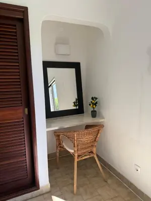 a mirror and a wicker chair in a room at Lemon Beach House - São Rafael in Albufeira