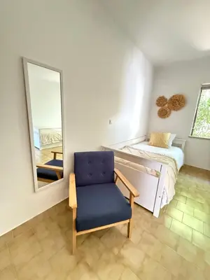 a bedroom with a mirror and a blue chair at Lemon Beach House - São Rafael in Albufeira