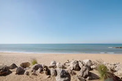 a group of rocks on a beach with the ocean at Quarteira Modern Flat in Quarteira
