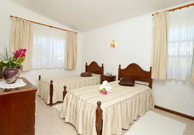 a bedroom with two beds and a vase with flowers at Oliveira by Vintage Travel in Guia