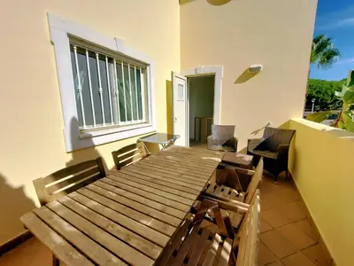 a wooden table and chairs on a balcony at Vilapeti by SAPvillas in Quarteira