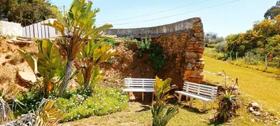 a stone wall with two benches in a garden at Quinta do Lagar - 02 in Albufeira