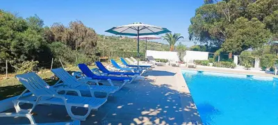 a row of blue chairs and an umbrella next to a swimming pool at Quinta do Lagar - 03 in Albufeira