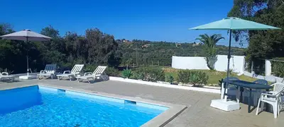 a swimming pool with chairs and a table and an umbrella at Quinta do Lagar - 06 in Albufeira
