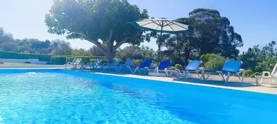 a group of chairs and an umbrella next to a swimming pool at Quinta do Lagar - 08 in Albufeira