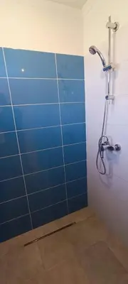 a bathroom with a shower with a blue tile wall at Quinta do Lagar - 09 in Albufeira